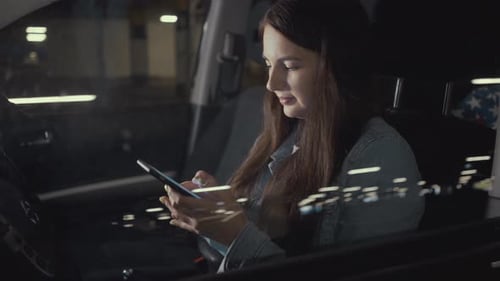 Woman Uses an Application on His Phone While Sitting in the Car in the Parking Lot