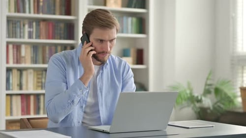 Adult on Smartphone Using Laptop at Desk