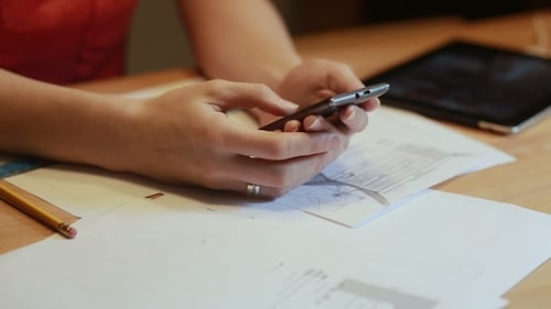 Hands Using Smartphone with Architectural Plans