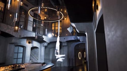 Female aerialist hanging on one leg and spinning upside down in a club.