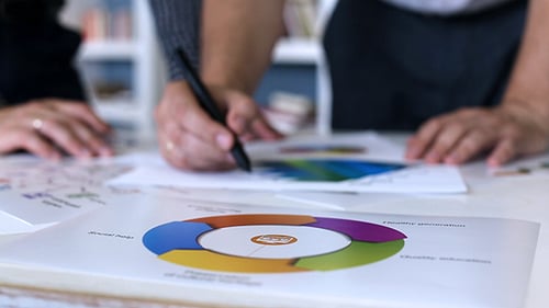 Businessmen Analyze Charts and Graphs on Table
