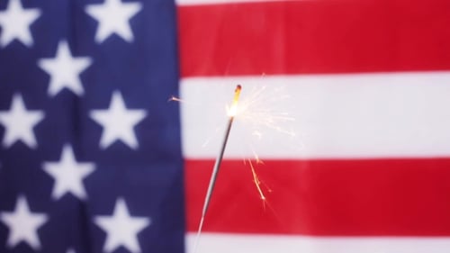 Sparkler Burning Against American Flag Background