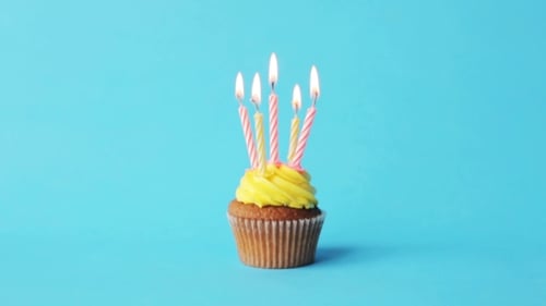 Cupcake with Burning Candles on a Light Blue Background