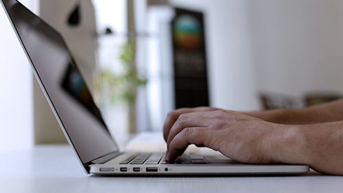 Hands Typing on Laptop in Bright Office