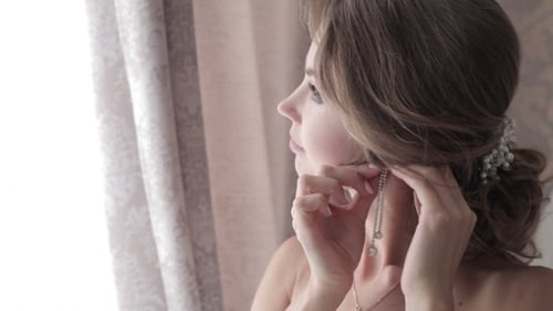 Beautiful Woman Puts on Pearl Wedding Earrings