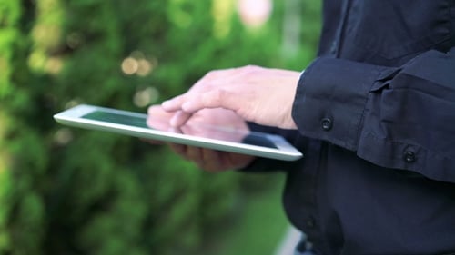 Man's Hands Touching And Using Tablet On Green Tree Background