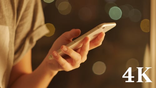 Woman Using Phone at Night With City Lights