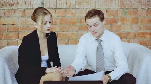 Businesswoman And Businessman Discussing Business With Charts On The Sofa