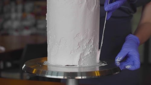 Woman Smooths White Icing on Cake with Spatula