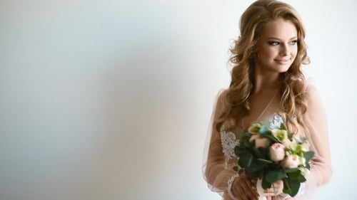Elegant Woman Holding Bouquet Posing in White Gown