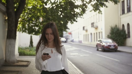 Woman Uses Smartphone Walking In Old City.