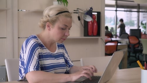 Woman Working on Laptop at Desk in Office