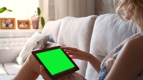 Beautiful Girl Using Tablet PC with Pre-keyed Green Screen Laying on Sofa at Home 5