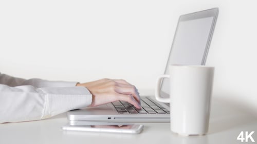 Hands Typing on Laptop at Clean White Desk
