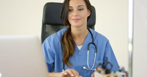 Young Adult Woman Doctor Typing at Desk