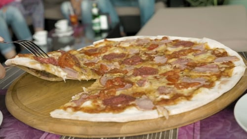 Eine Pizza schneiden mit Hilfe einer Gabel und eines Messers