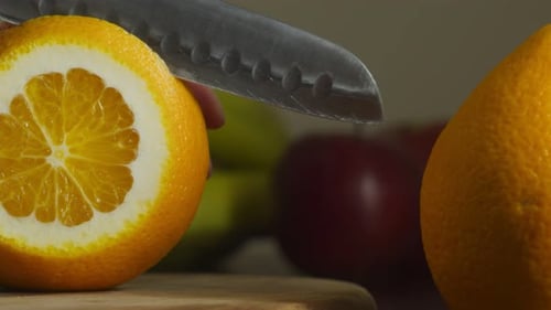 Primer plano de una mano con cuchillo de cocina para cortar naranjas en interiores