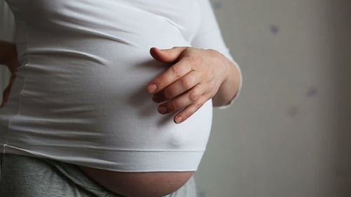 Pregnant Woman Gently Caressing Baby Bump in Home