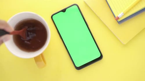 Top View of Smart Phone and Notepad on Yellow Background