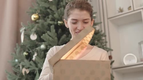 Woman Opening Christmas Gift with a Smile