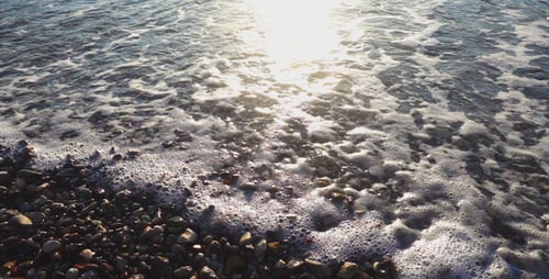 Meereswellen schäumen Sonnenlicht und Steine am Meer