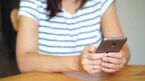 Woman Using Smartphone Device at Table Indoors