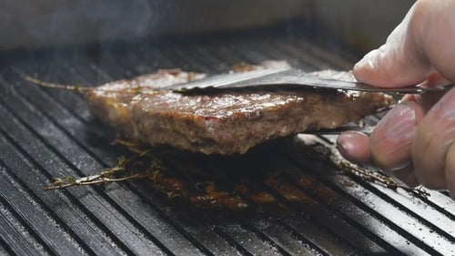 A Cook Turns Up a Steak Of Meat On a Grill In
