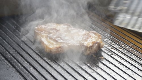 A Cook Turns Up a Steak Of Meat On a Grill In