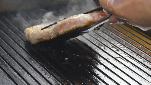 A Cook Turns Up a Steak Of Meat On a Grill In