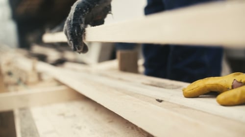 Gloved Hands Carefully Stacking Pieces of Lumber