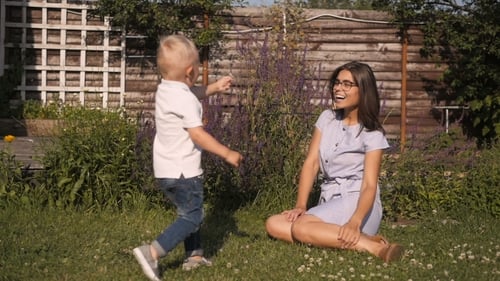 Woman and Child Interact on Grass Lawn