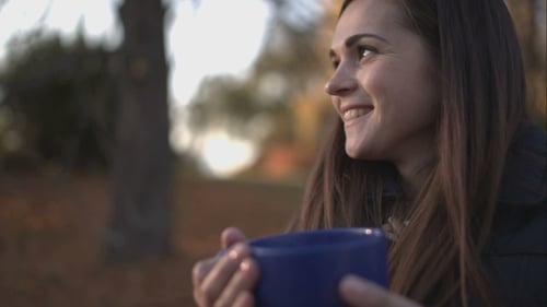 Woman Drinking Tea In The Park In Autumn.