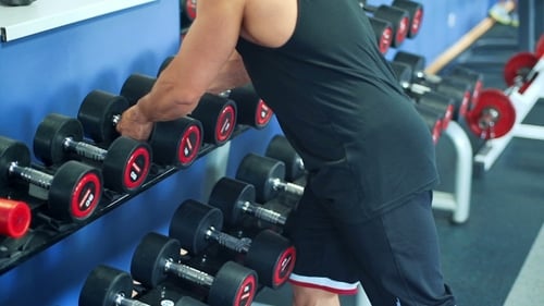 Strong Man's Hand Takes a Heavy Dumbbell In Gym