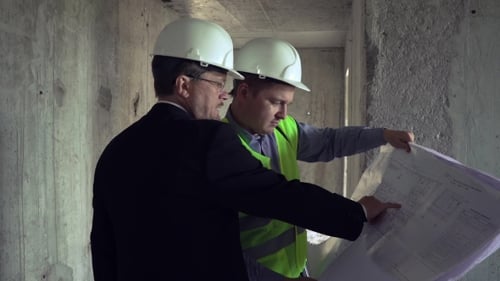 Arquiteto e capataz discutindo o plano de construção