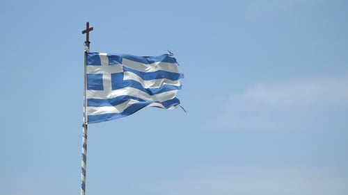 Flag Waving on Pole Against Blue Sky