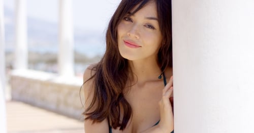 Young Woman Standing Watching From Behind a Pole