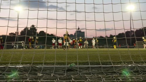 Football Team Practice at Sunset Seen Through Goal