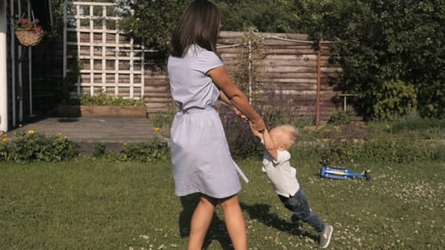 Happy Mother And Son Spinning In The Garden. Mom And Son Having Fun