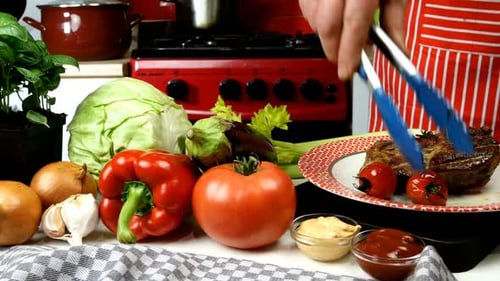 Chef Plating Steak and Vegetables in Kitchen