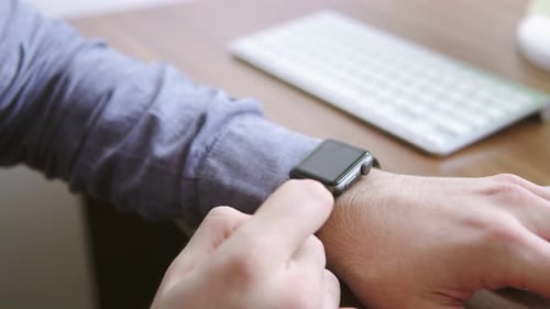 Ein Geschäftsmann verwendet eine Smartwatch an seinem Schreibtisch, um einen Termin zu vereinbaren