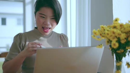 Woman Using Laptop and Eating at Home