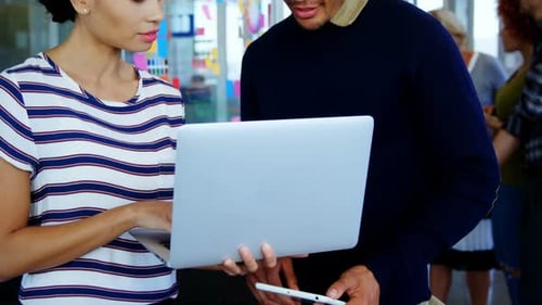 Colleagues Discuss Work Using Laptop and Tablet
