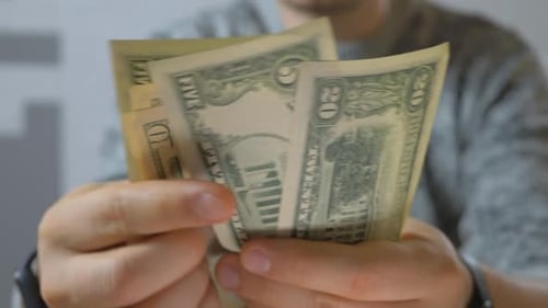 Man Holds Cash Bills in Hand Close Up