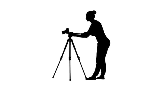 Operator Works With The Camera On a Tripod. Silhouette.