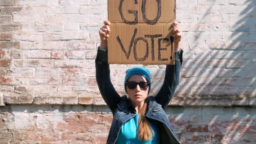 Woman shows cardboard Go Vote sign Voting balloting polling Political choice elections voice 4K