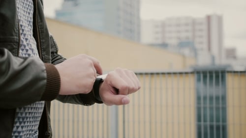 Adult Uses Smartwatch in Urban Setting