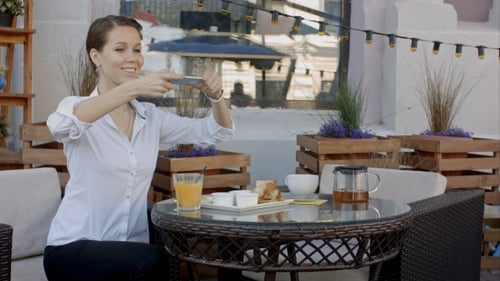 Woman at Cafe Taking Photos with Phone
