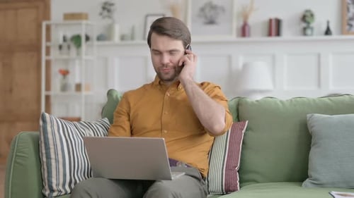 Man Working at Home on Laptop and Smartphone