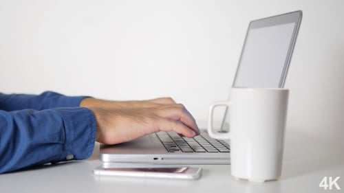 Hands Typing on Laptop Keyboard at Desk