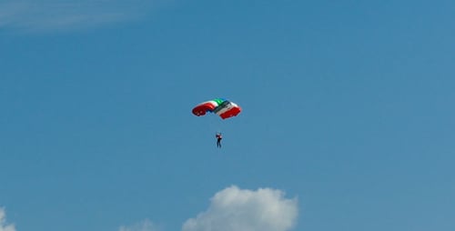 Skydiver Descends with Parachute in Bright Blue Sky